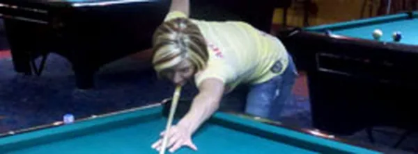 Girl playing pool at Cue's Billiards in Marietta A woman taking a shot during a game at Cue's Billiards